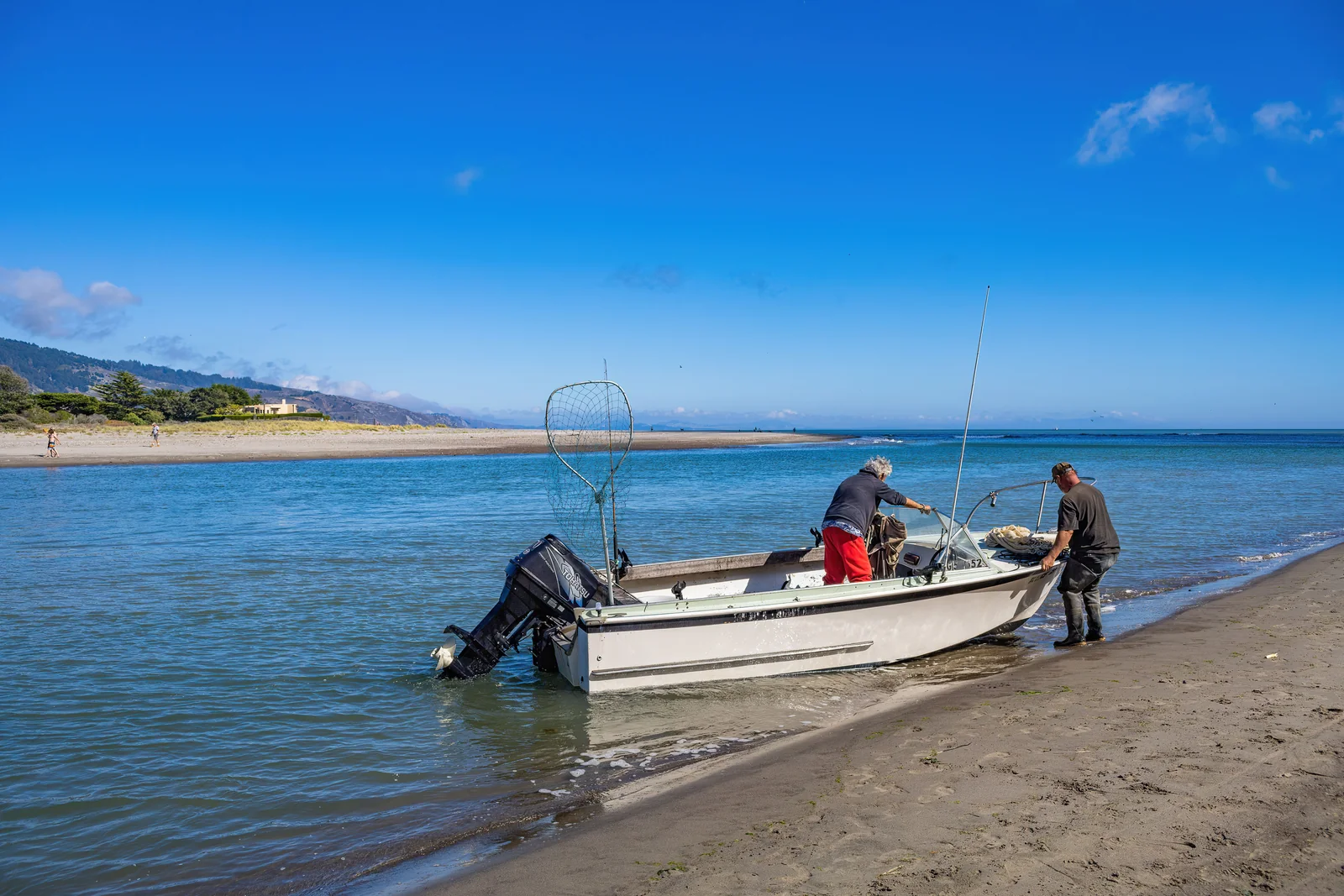 Dos personas preparando una pequeña embarcación a la orilla de la playa
